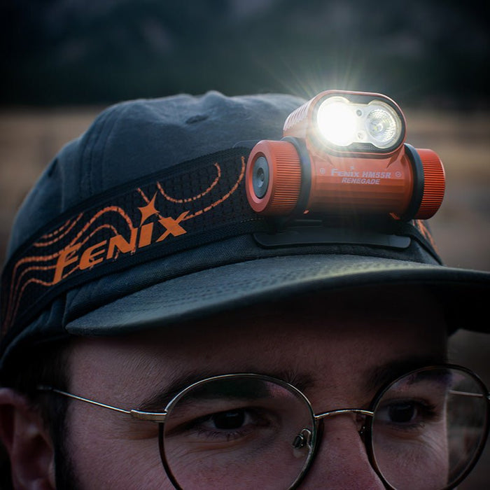 Person wearing a cap with a Fenix HM55R RENEGADE headlamp with the light on