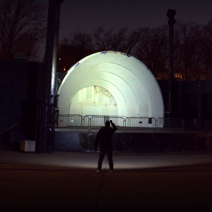 Person holding the Fenix LD30 RENEGADE illuminating a large illuminated dome structure at night
