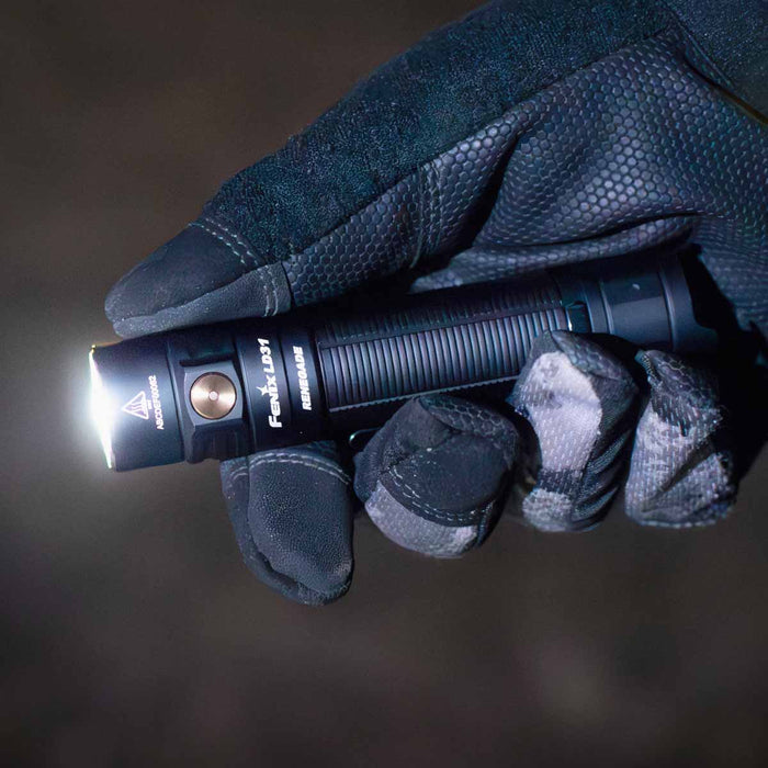 Hand wearing a dark glove holding a Fenix LD31 RENEGADE Flashlight with a dark background