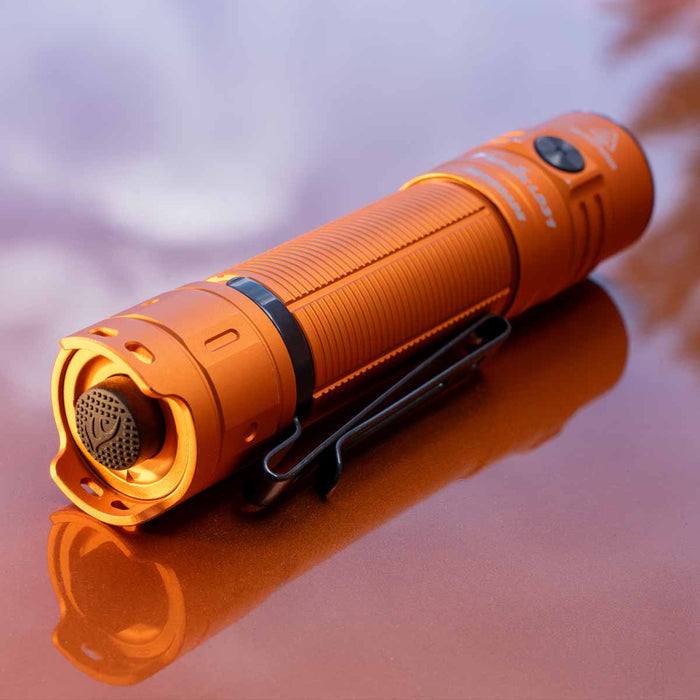Orange Fenix LD31 RENEGADE Flashlight on a reflective surface with a blurred background
