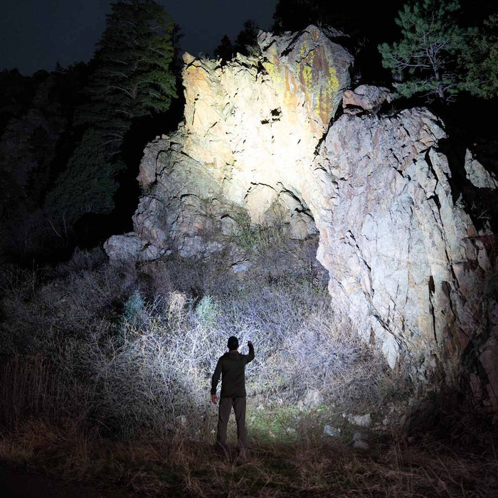 Person using a Fenix LD31 RENEGADE Flashlight to illuminate rocky terrain at night