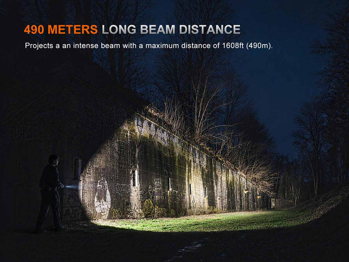 Person using the Fenix TK15R to illuminate an old building at night with text about long beam distance.
