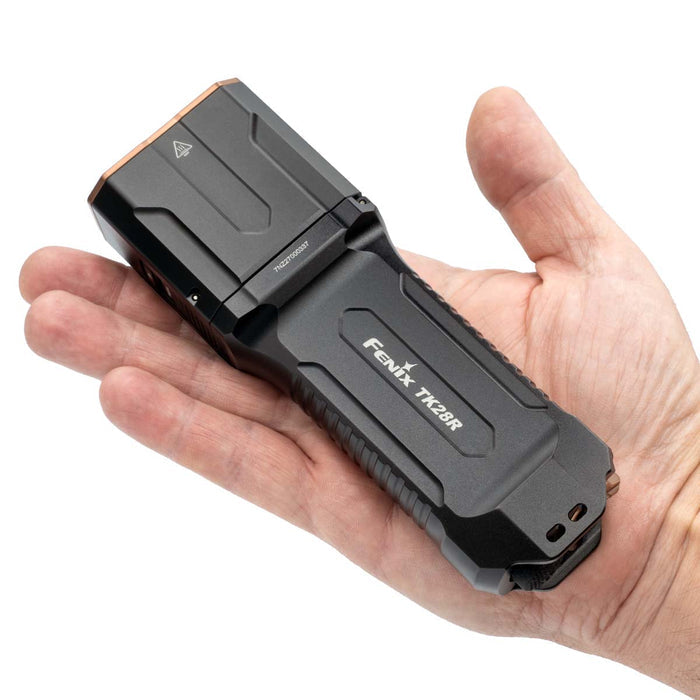 Fenix TK28R flashlight held in a hand to show size on a white background